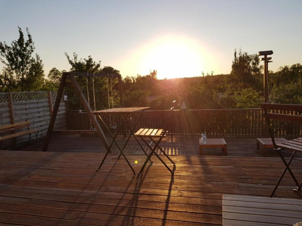 zachód słońca na tarasie ze stołem i huśtawką w obiekcie Spa Apartamenty Lidzbark w mieście Lidzbark