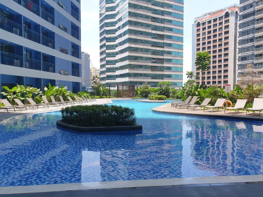 a large swimming pool with chairs and buildings at Heart of Makati, Fully furnished condo, cbd central location in Manila