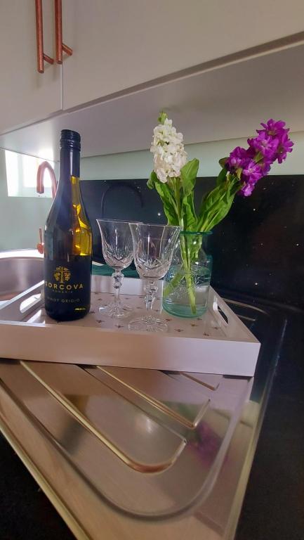 a bottle of wine and two glasses and flowers on a counter at Lake View Lodges in Long Melford