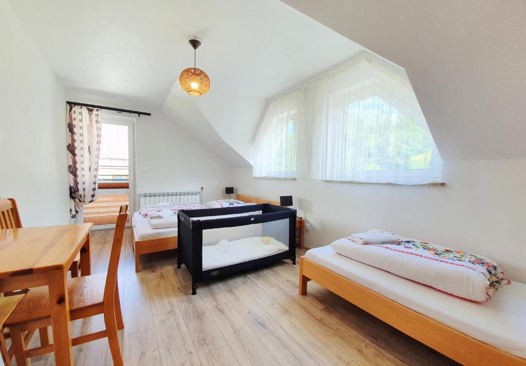 オホトニツァ・グルナにあるPokoje Czajkaのベッド2台、テーブル、窓が備わる客室です。