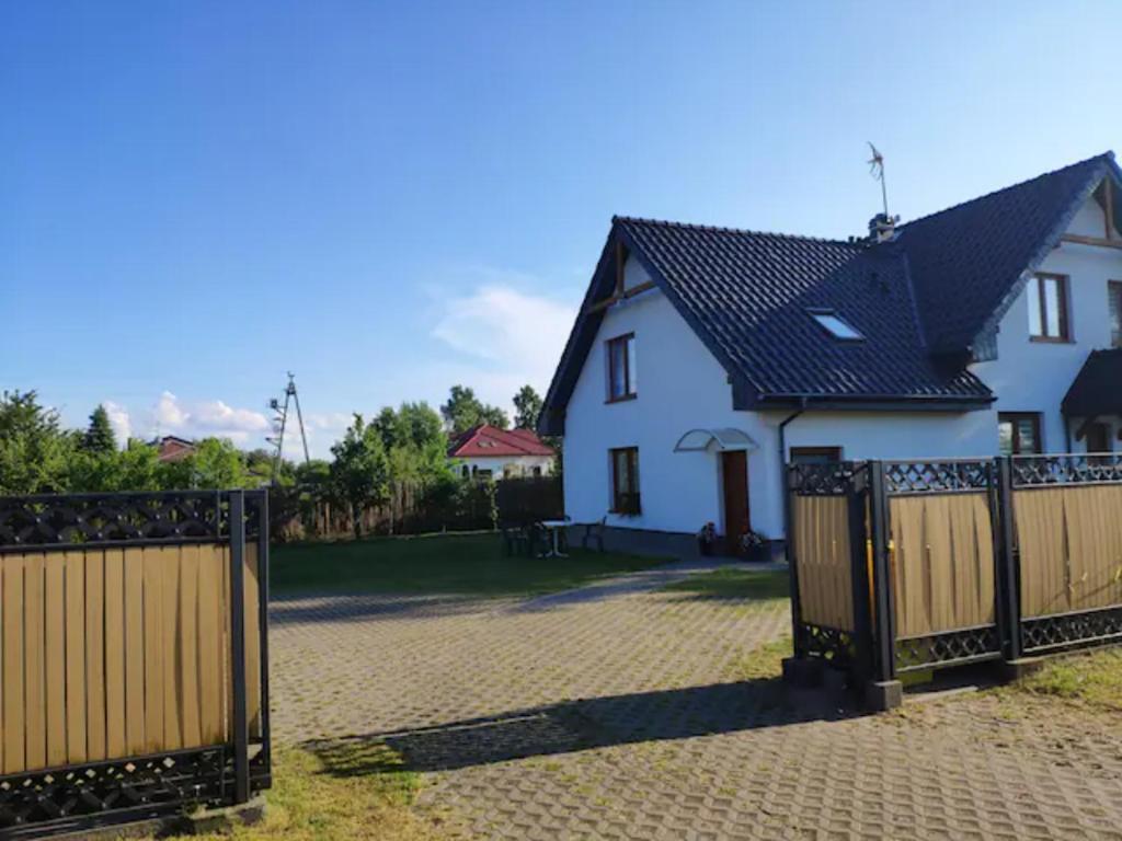una casa bianca con tetto nero e cancello di Domek pod brzozami a Grzybowo