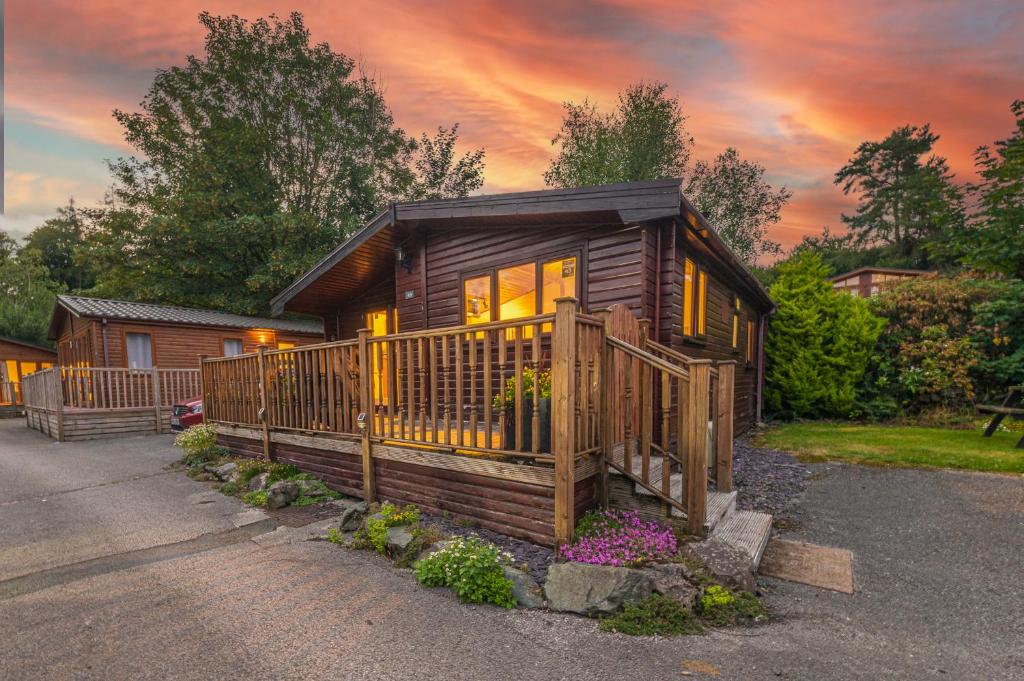 a log cabin with a porch and a house at Bowness 45 - 2 bedroom Lake Windermere Lodge in Windermere