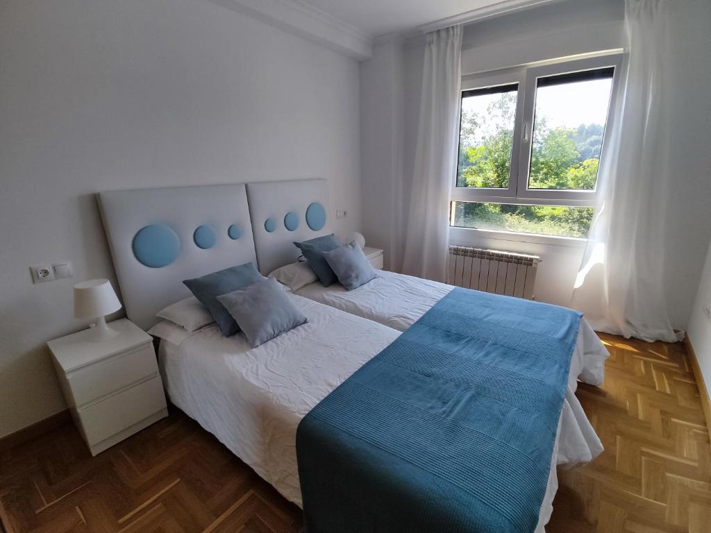 1 dormitorio con 1 cama grande con almohadas azules en Apartamento MAR y MONTAÑA ASTURIAS, en Posada de Llanes