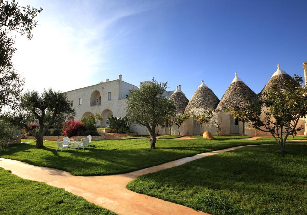 a building with a grass yard with trees and a path at Masseria Cervarolo in Ostuni