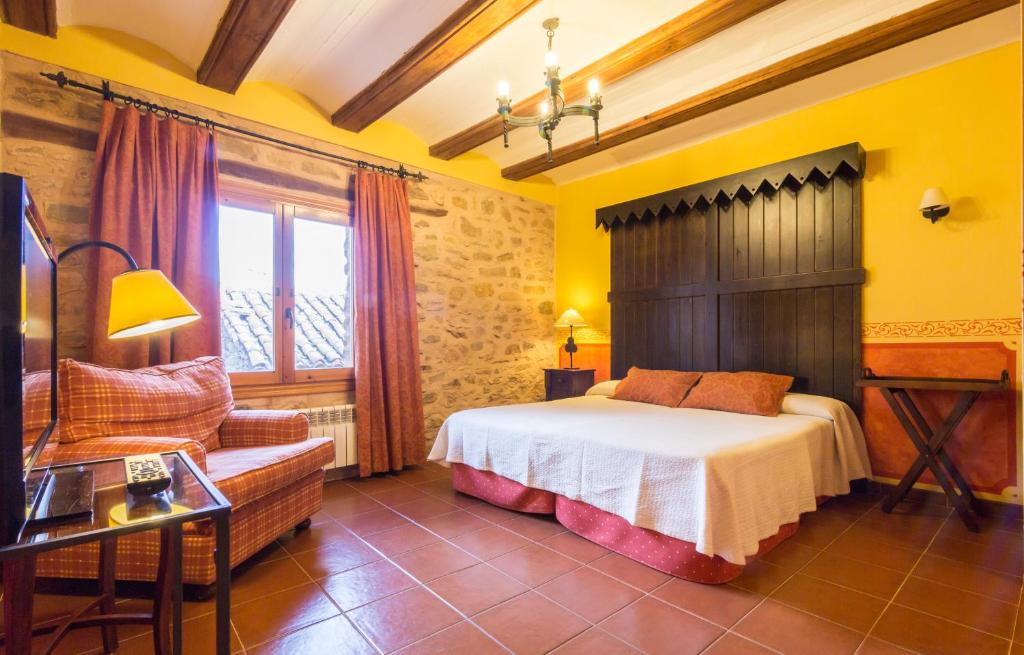 a bedroom with a bed and a chair and a window at Casa Rural La Yedra in Galve