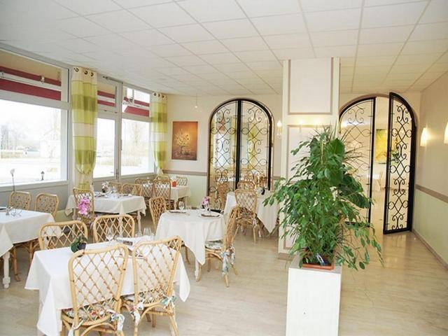 un restaurant avec des tables blanches, des chaises et des fenêtres dans l&#39;établissement Le Chagny, à Chagny