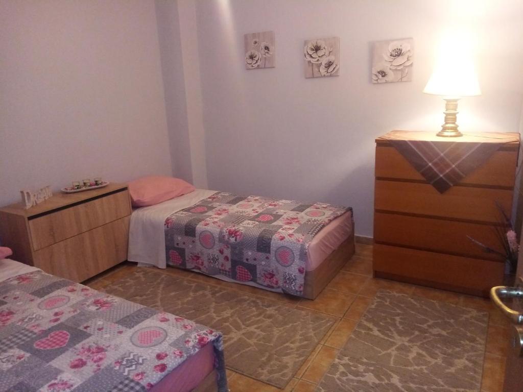een slaapkamer met 2 bedden en een dressoir met een lamp bij Haras'house in Asvestokhórion