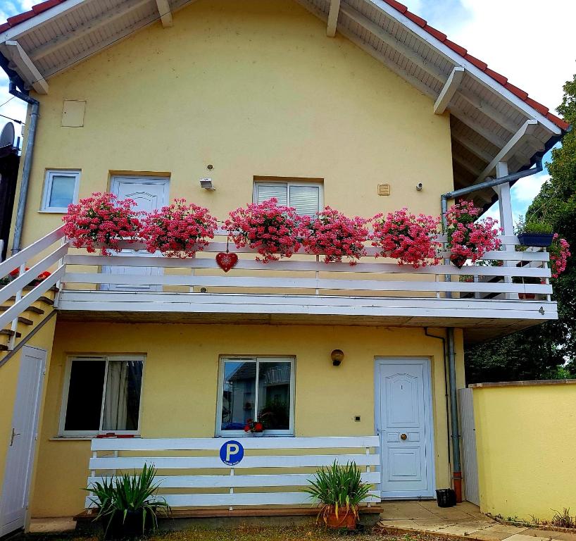 a yellow house with pink flowers on a balcony at GEO 2 in Horbourg