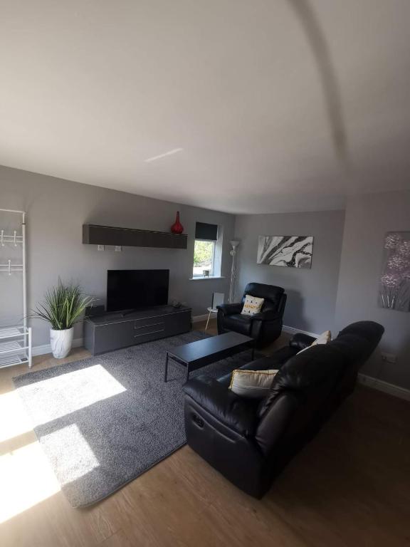 a living room with a black leather couch and a tv at Green Street Retreat in York