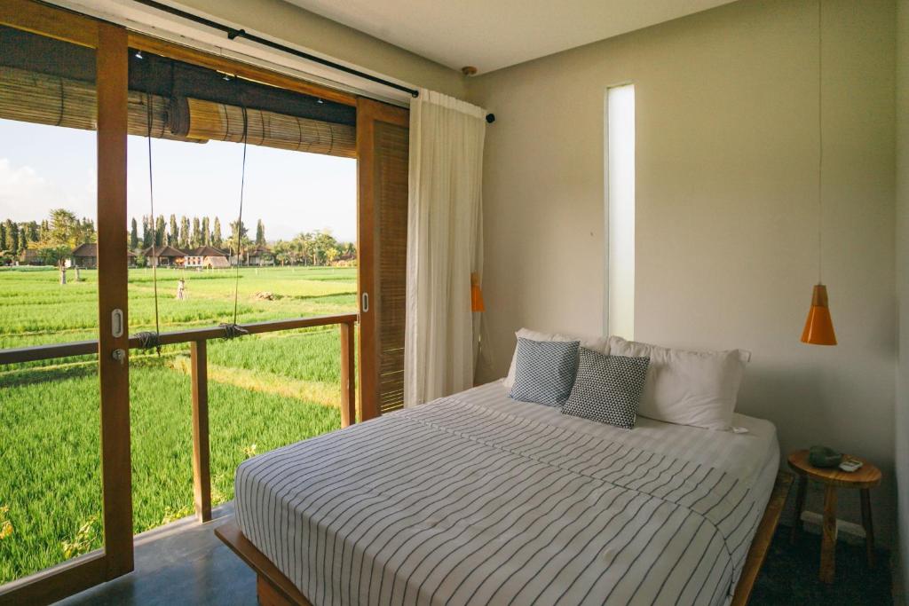 een slaapkamer met een bed en uitzicht op een veld bij Casa Avana in Ubud