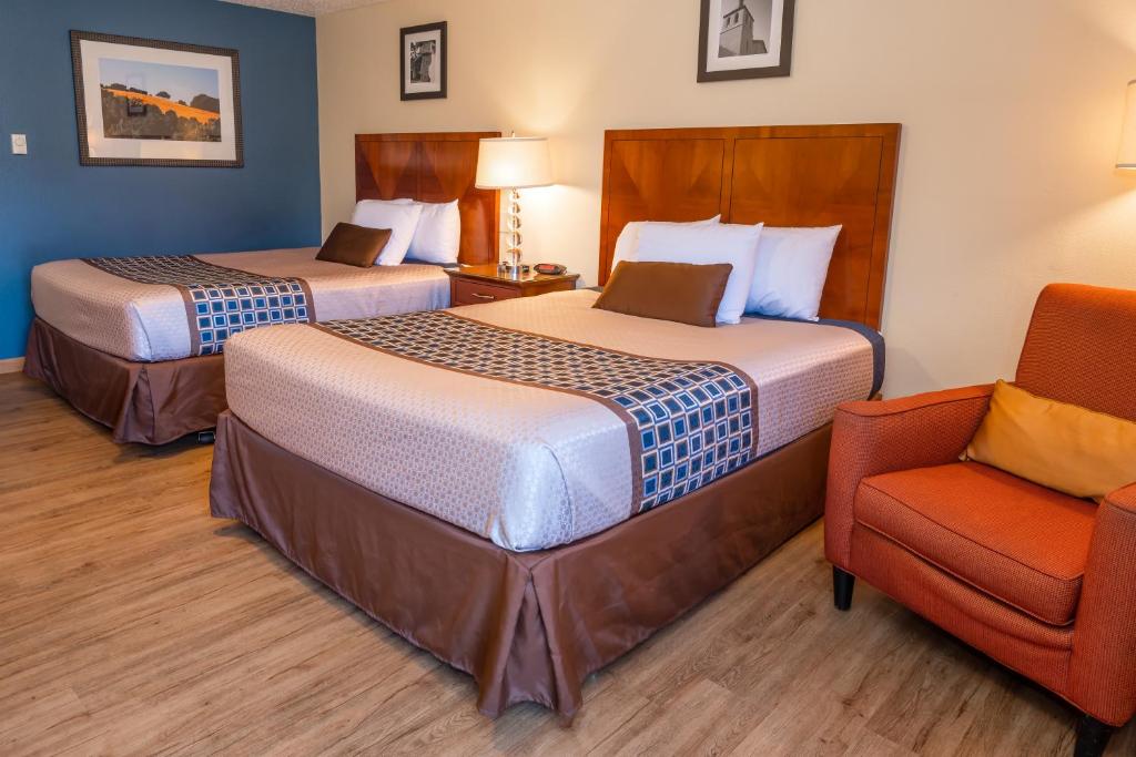 a hotel room with two beds and a chair at Riviera Inn in Port Angeles