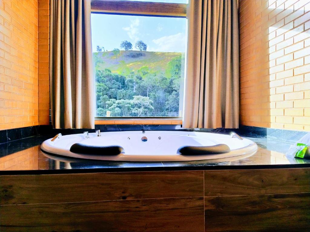 a bath tub in a bathroom with a window at Chalés Estância Campestre in Capitólio