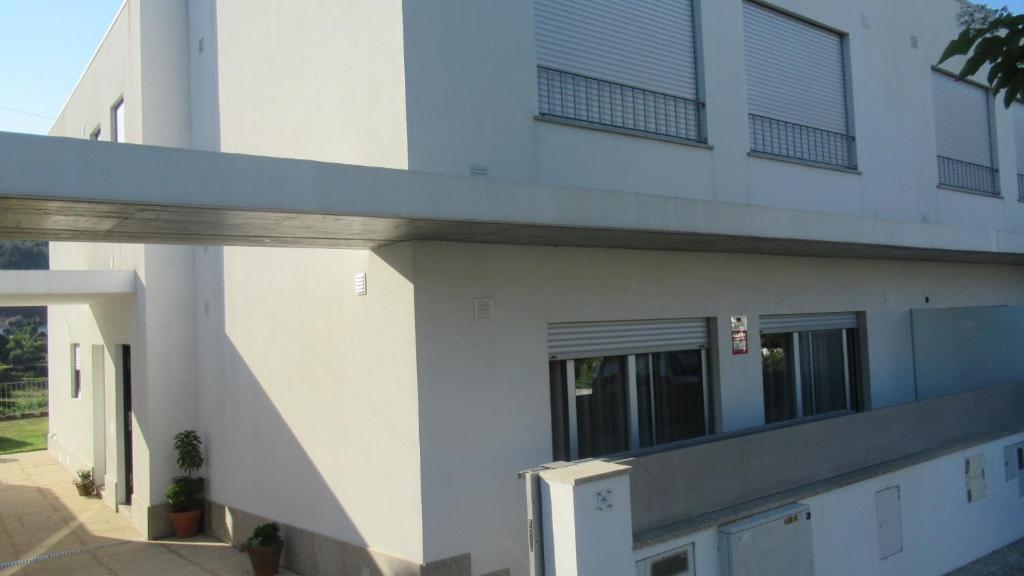a white building with windows and a sidewalk at AL CASA DE SÃO ROQUE in Caminha
