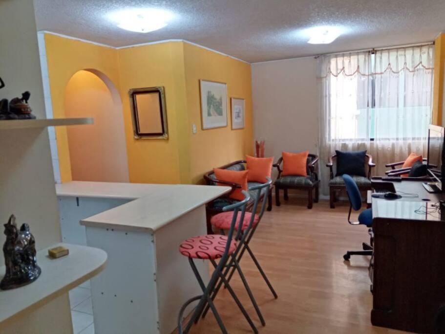 a room with a bar with chairs and a desk at Hermoso Apartamento al Norte cerca de la Embajada Americana in Quito