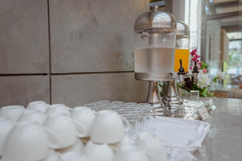 A beverage station with chilled water, juice, glasses, and white cups.