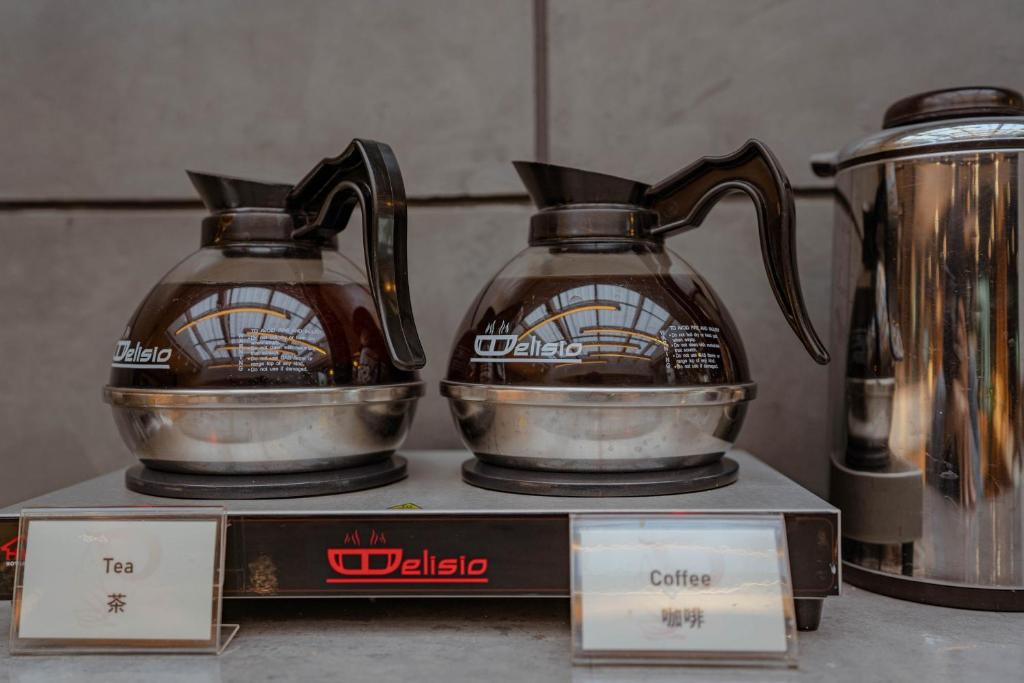 A self-service station offering labeled tea and coffee from thermal pots.