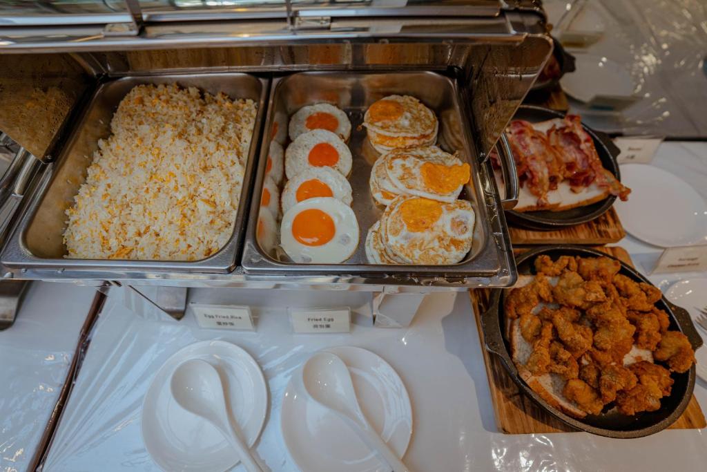 A buffet counter with rice, eggs, bacon and fried chicken.