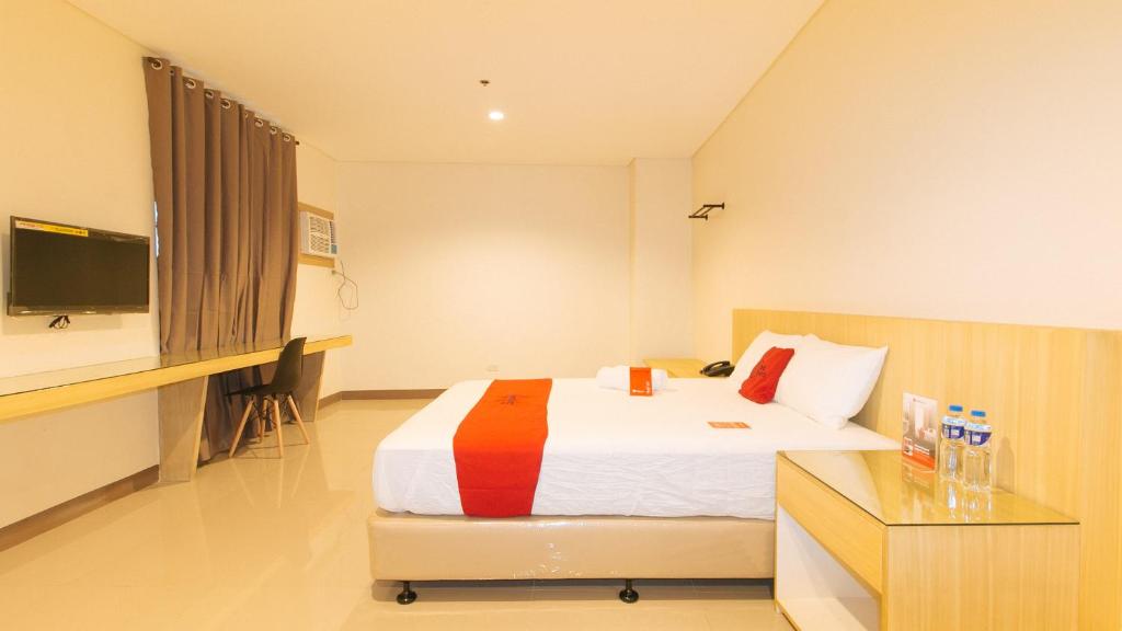 um quarto com uma cama, uma secretária e uma televisão em RedDoorz Plus @ Kaizen Suites Taft Avenue em Manila