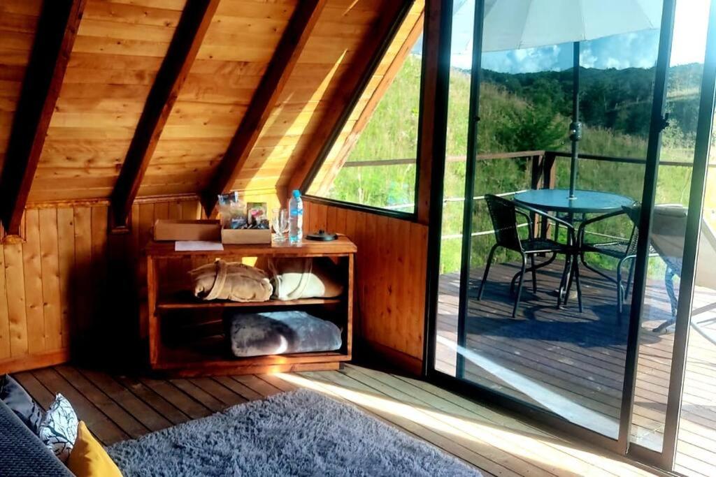 eine Holzhütte mit einem Tisch und einer Glastür in der Unterkunft Carriquí Glamping in Gómez Plata