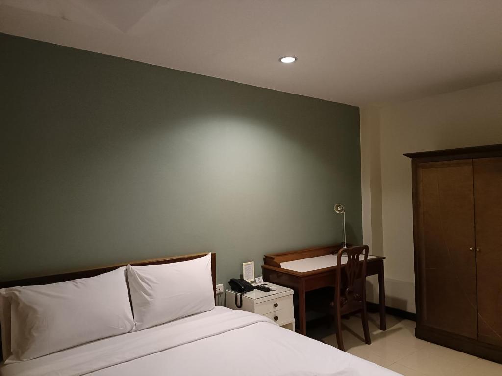 A bedroom corner with a compact desk, chair, telephone and wardrobe beside the bed.