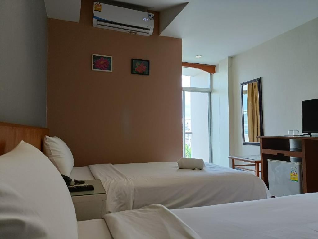 A twin bedroom with two beds, a television console, mirror and bright glazed opening.