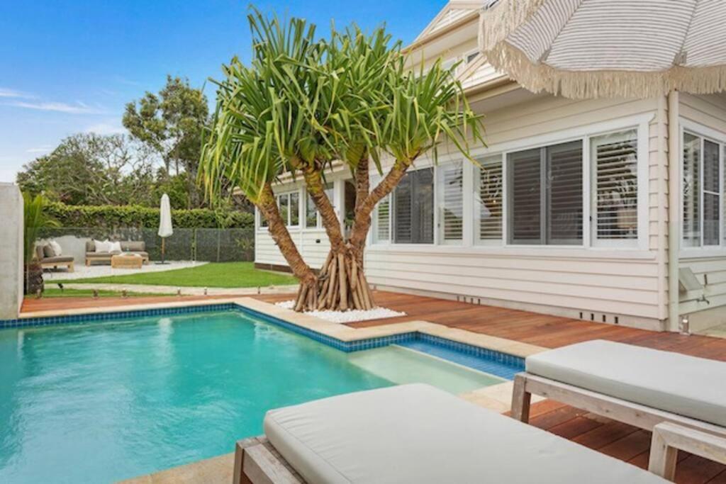 a house with a swimming pool and a palm tree at Fuller Holidays - Hacienda, Luxury 5 bedroom home with pool in Byron Bay