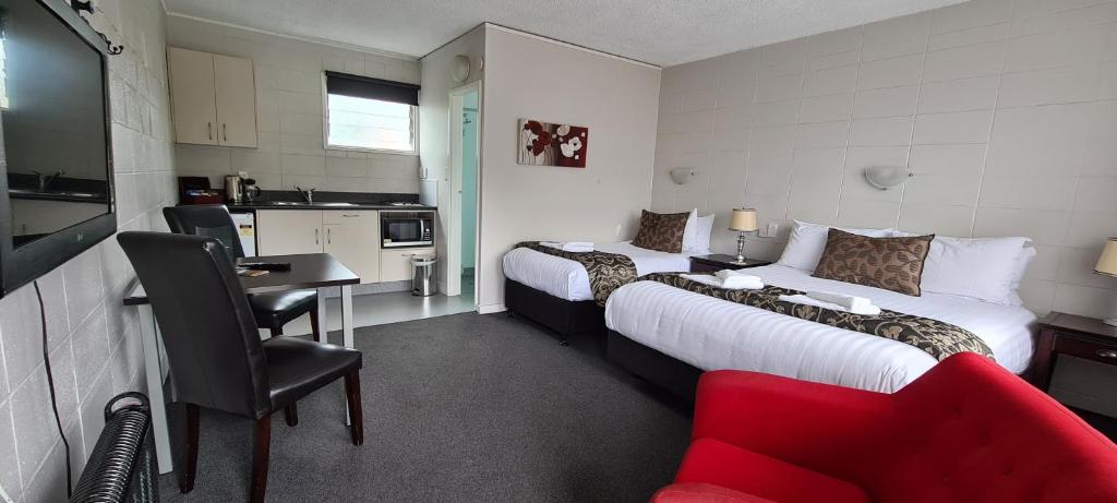 a hotel room with two beds and a red couch at Forgotten World Motel in Taumarunui