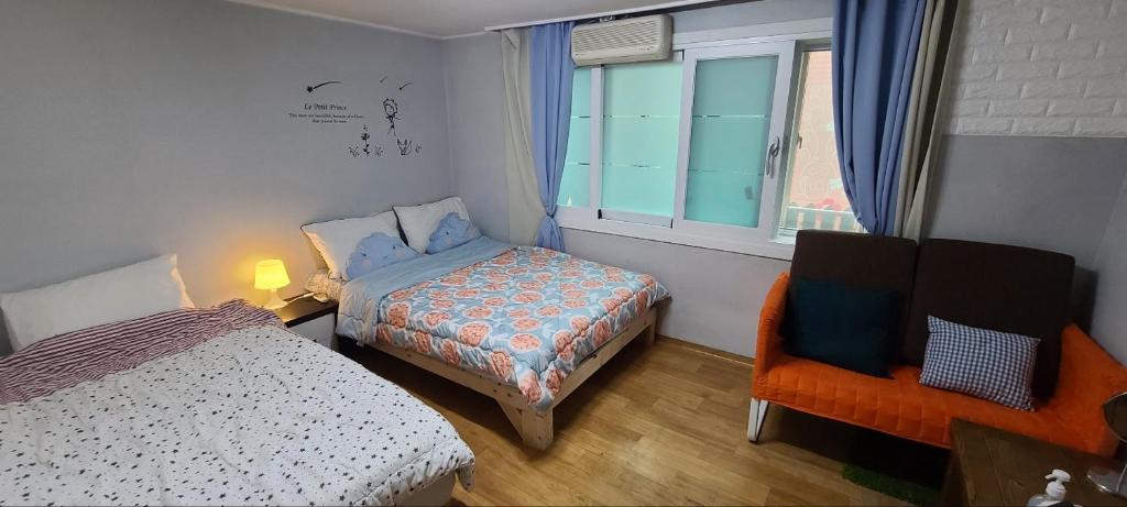 a bedroom with a bed and a chair and a window at Appletree Guesthouse in Seoul