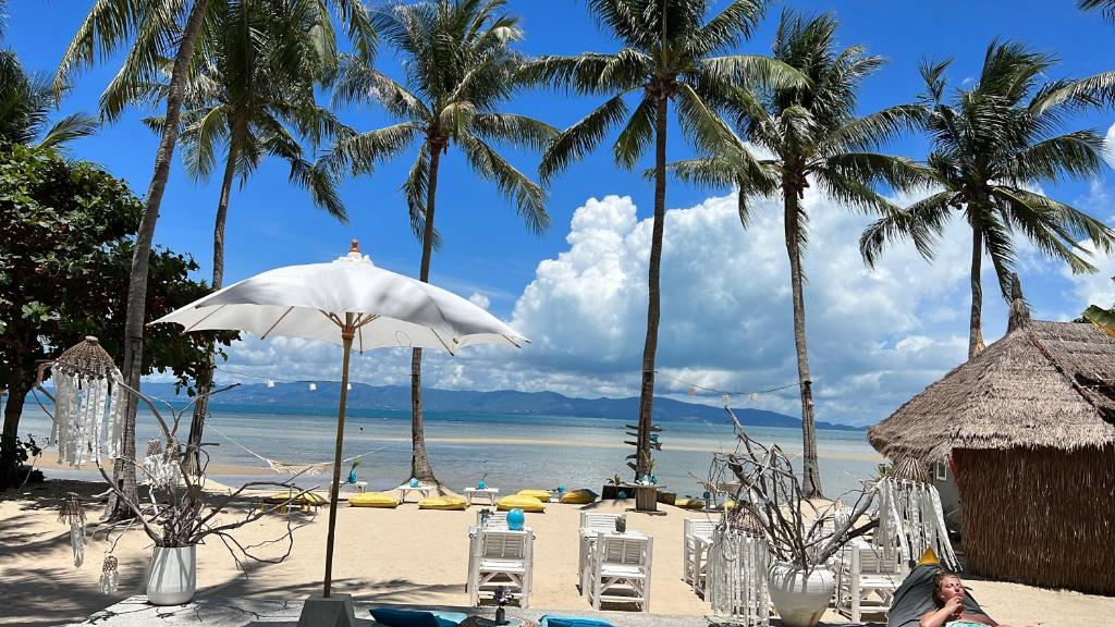 a beach with chairs and an umbrella and palm trees at Sea Love Beach Bar & Bungalows in Ban Tai
