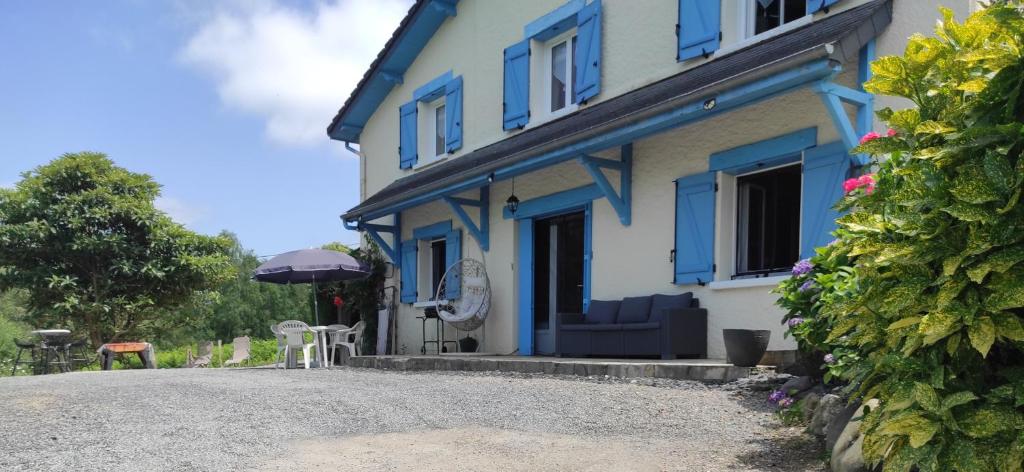 Casa azul y blanca con silla y sombrilla en Gîte des 3 arbres en Aramits