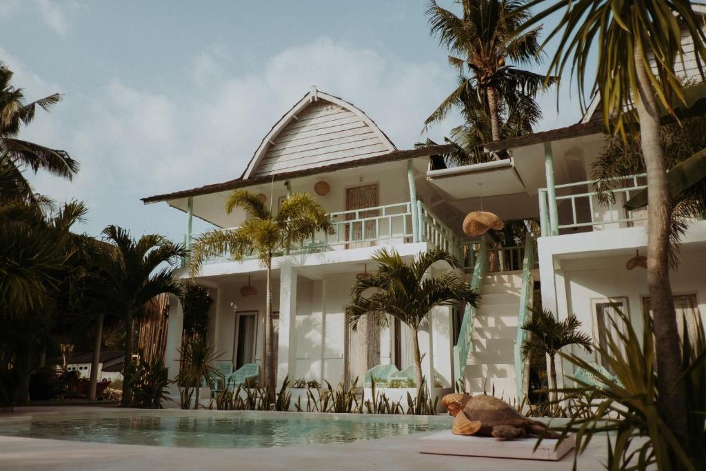 a dog laying next to a house with a swimming pool at La Isla Bonita Gili Air in Gili Air