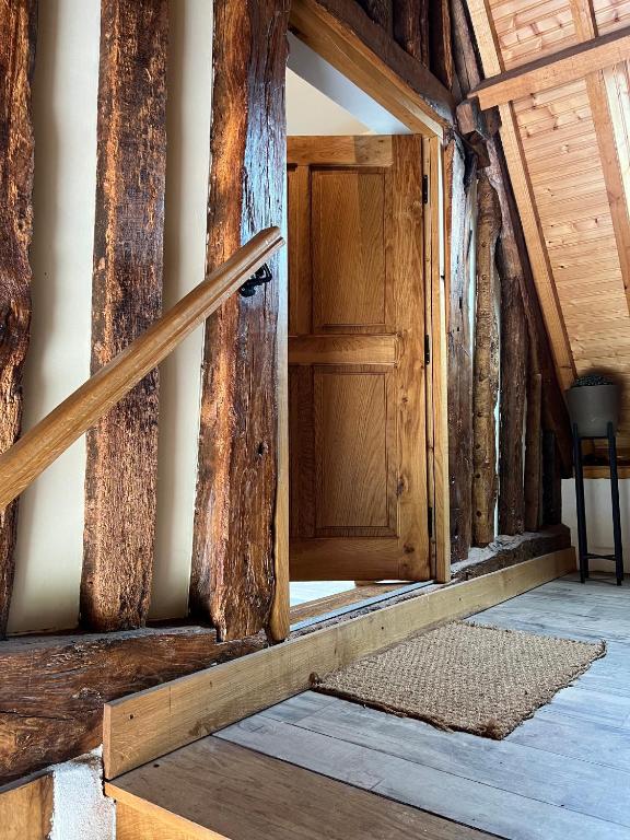 - une porte en bois ouverte dans une chambre avec un tapis dans l'établissement Le Domaine des Bois, à Blangy-le-Château