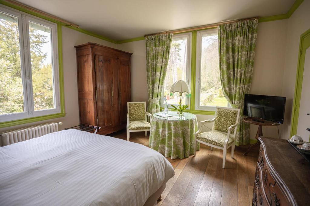 - une chambre avec un lit, une table et des chaises dans l'établissement Le Manoir des Impressionnistes - Bord de Mer, à Honfleur