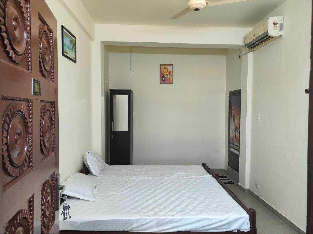 1 dormitorio con 1 cama blanca en una habitación en Jinnens Tourist Home, en Ponnāni