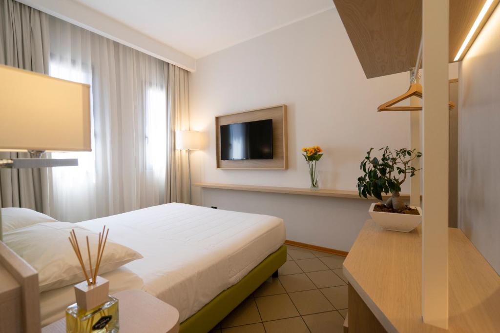 Hotel Ostuni في ريميني: غرفة فندق بسرير وتلفزيون