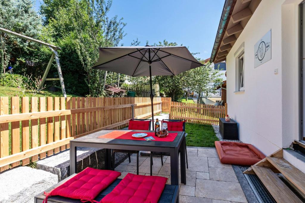 a patio with a table with red cushions and an umbrella at Ferienwohnung Ronja 