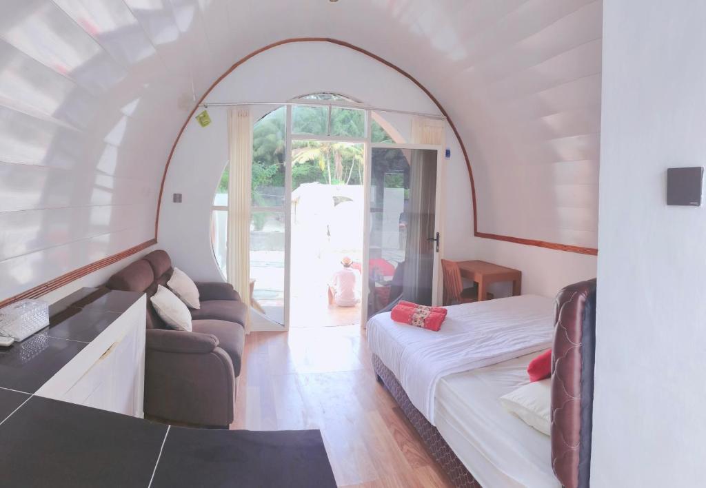 1 dormitorio con 1 cama y 1 sofá en una habitación en Mercy Cottage en Langgur
