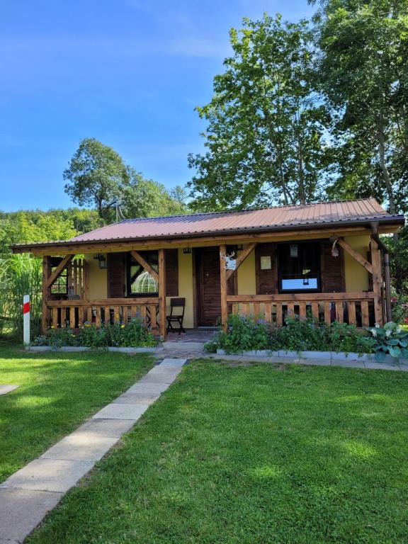 a log cabin with a porch and green grass at Domki Białogarda in Wicko