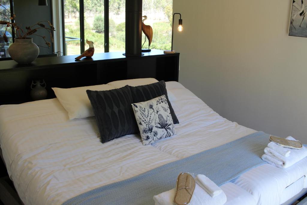 a large white bed with shoes on top of it at Softfoot Farm Luxury Retreats in Hindmarsh Valley