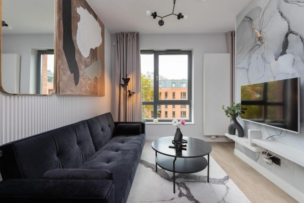 a living room with a black couch and a table at Gdańsk Śródmieście Akademia Muzyczna Apartment by Renters in Gdańsk