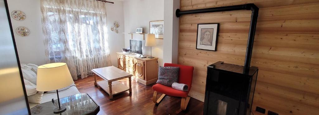 sala de estar con silla roja y pared de madera en Appartamento Adalpina, en Santo Stefano di Cadore