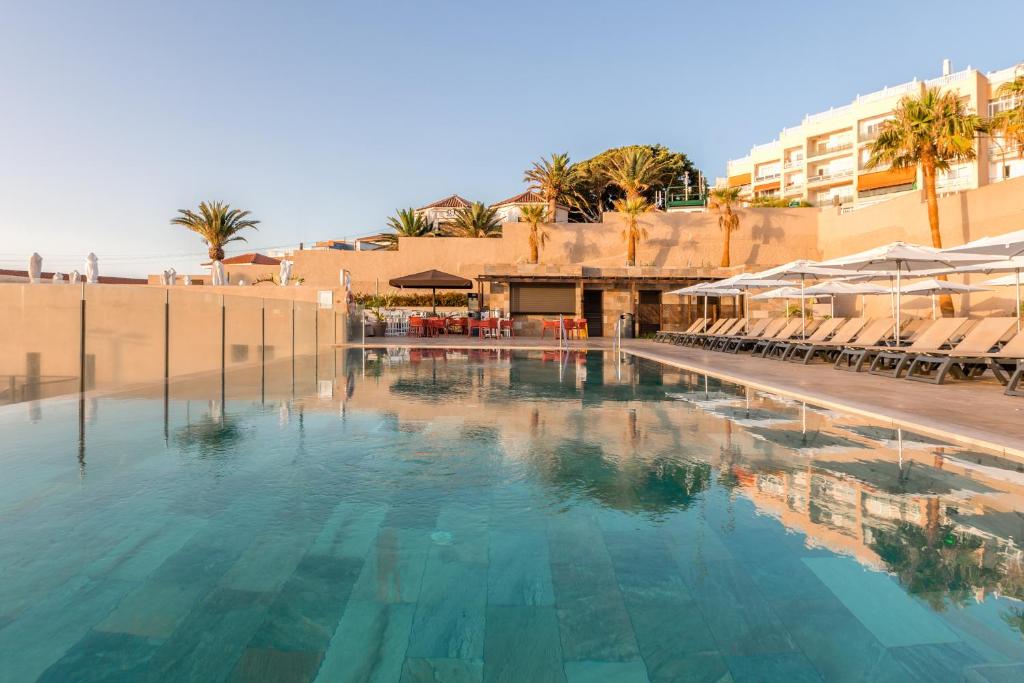 a large swimming pool with chairs and a building at Catalonia Punta del Rey in Candelaria