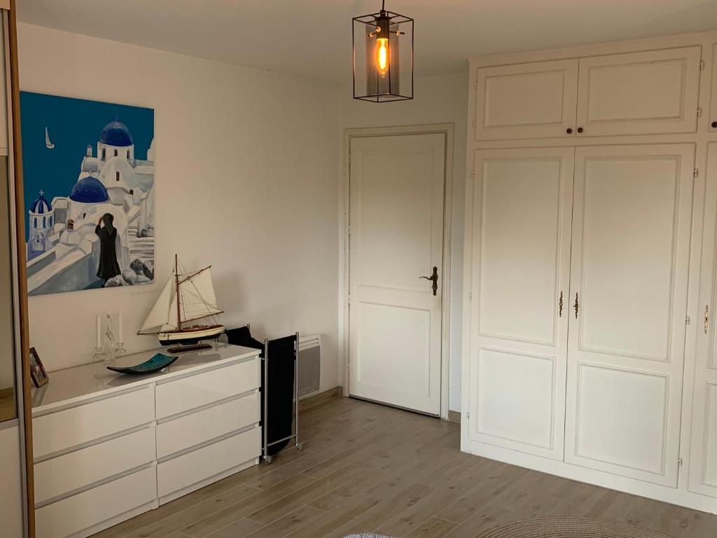 a living room with white cabinets and a tv and a painting at Appartement spacieux et lumineux in Sélestat
