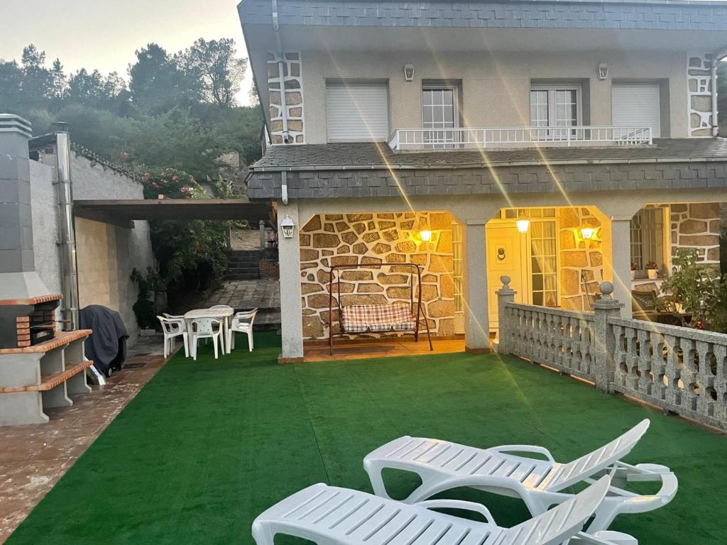 a patio with white chairs on a green lawn at Casa do Pombar en Valdeorras in Seadur