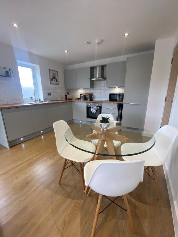 a dining room with a glass table and white chairs at Modern 2 Bed Apartment/Free Parking/Near City/Self-Check In in Handsworth
