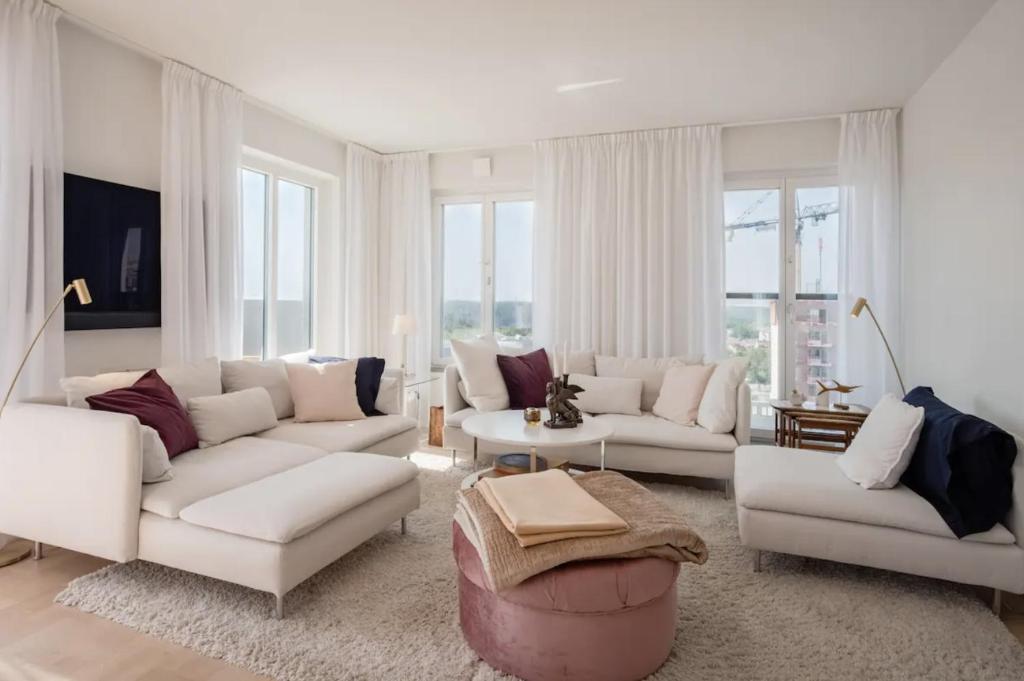a living room with white furniture and windows at Stadsporten Nacka in Nacka