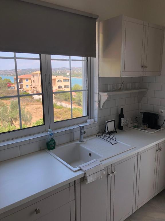 uma cozinha com um lavatório e uma janela com vista em Venetia apartment em Porto Heli