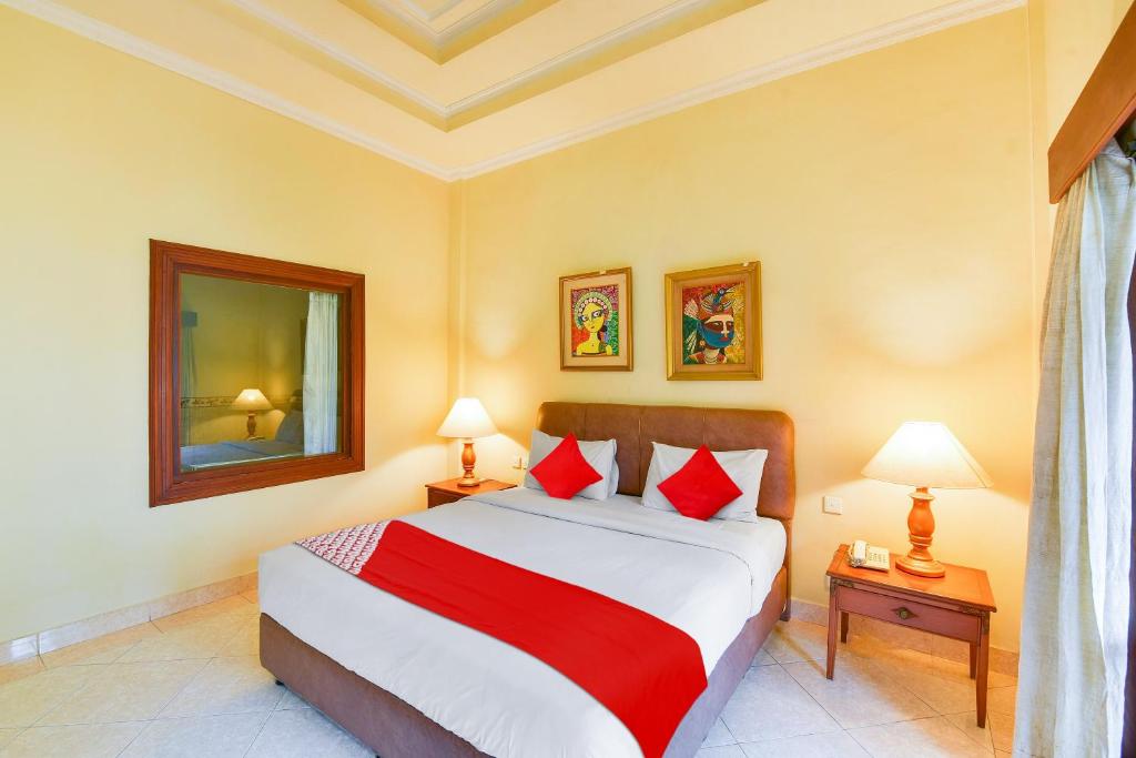 una camera da letto con un grande letto con cuscini rossi di Super OYO Townhouse Oak Maxi Hotel Legian a Kuta