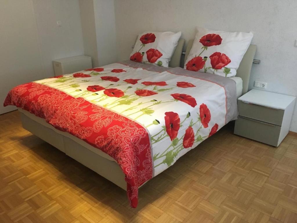 a bedroom with a bed with red flowers on it at Ferienwohnung am Ziegelbach mit Balkon in Hechingen