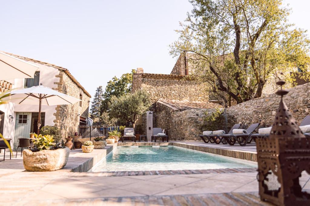 a pool with chairs and an umbrella in a yard at Hotel Monells Summum in Monells